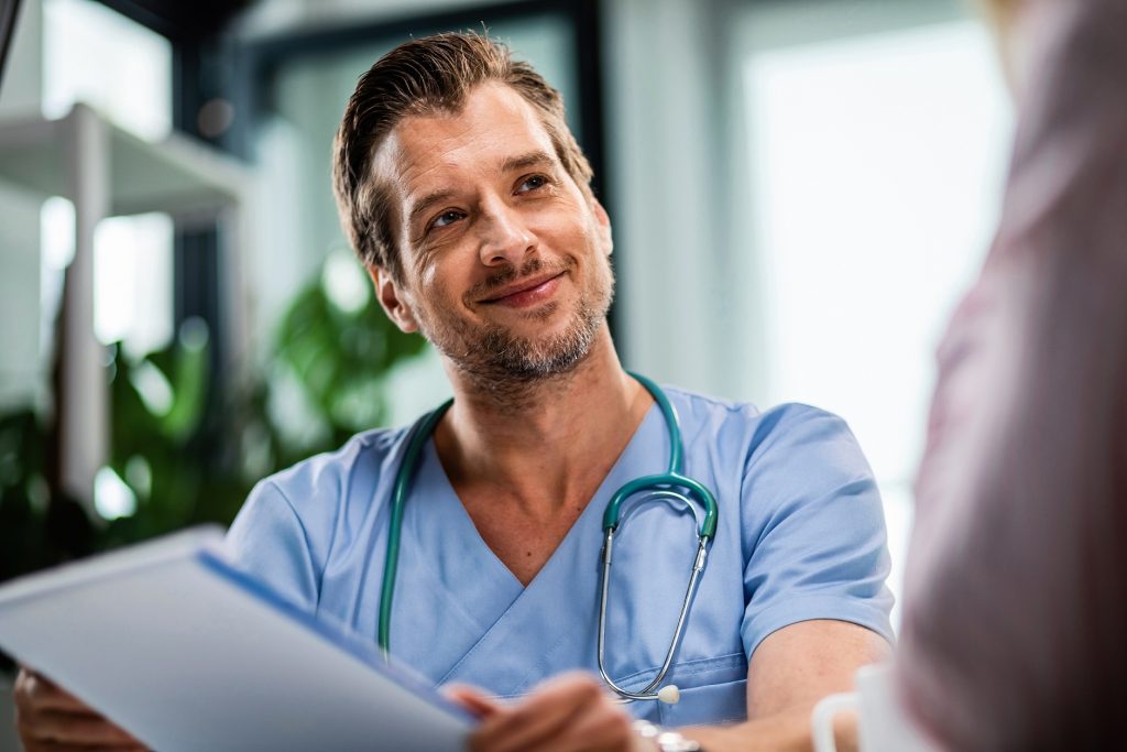 Happy Doctor Holding Medical Paperwork While Communicating Patient Medical Appointment Hospital