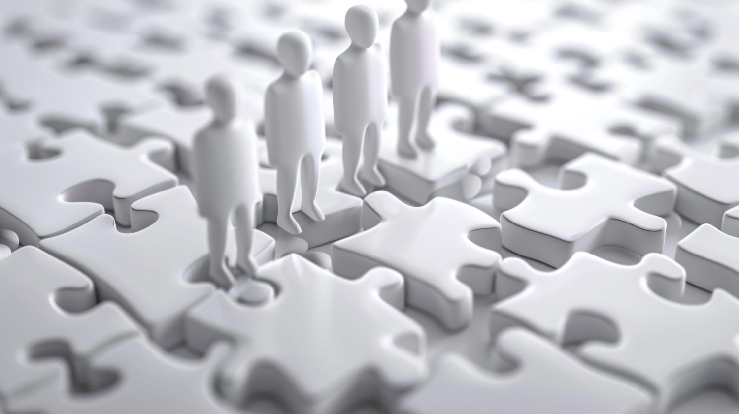 puzzle with people standing around it with one holding puzzle piece