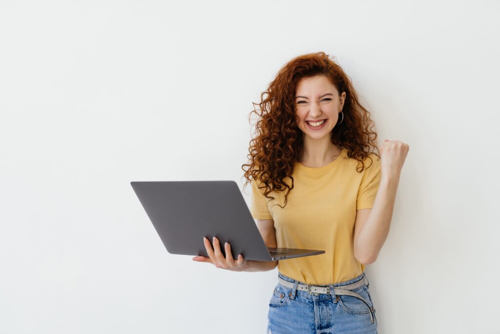 retrato de una mujer joven y bonita celebrando un exito en un portatil aislado de fondo blanco 1 1